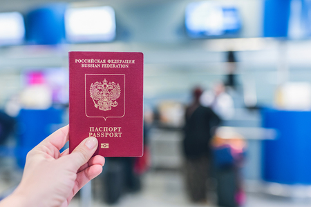 Female holding russian pasport opposite airport board.の写真素材