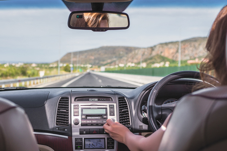 Young woman is driving on the highway in Italy and using gps navigation app on the mobile phone. View from the back seat of the carの写真素材
