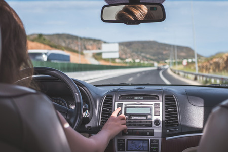 The girl is driving on the highway in Italy. View from the back seat of the car on the windshield, road and the driverの写真素材