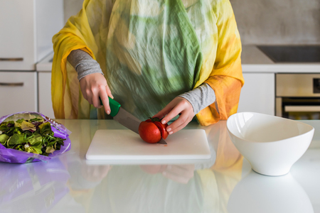 Muslim woman chopping tomatoes in kitchen . Salad preparationの写真素材