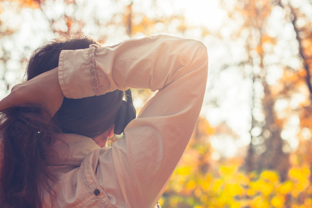 Female with headphones walking on the park listen sounds or music of autumn forest. Concept. Indian summer seasonの写真素材