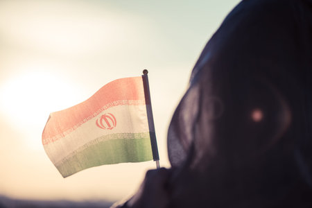 Muslim woman in scarf with Iranian flag at sunset.Concept