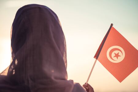 Muslim woman in scarf with Tunisia flag of at sunset.Conceptの写真素材