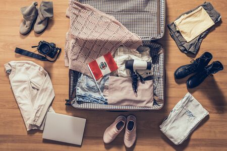 Woman's clothes, laptop, camer and flag of Mexico lying on the parquet floor near and in the open suitcase. Travel conceptの写真素材