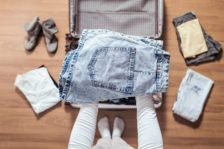 Top view of woman hands packing a luggage for a new journey.