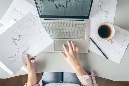 Top view. Young business woman sitting at table with cup of coffee and working on the laptop with...