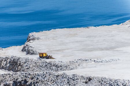 Aerial view of opencast mining quarry with one machinery on the blue sea backgroundの写真素材