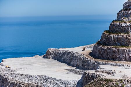 Aerial view of opencast mining quarry with one machinery on the blue sea backgroundの写真素材