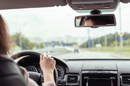 woman is driving on the highway. View from the back seat of the carの写真素材