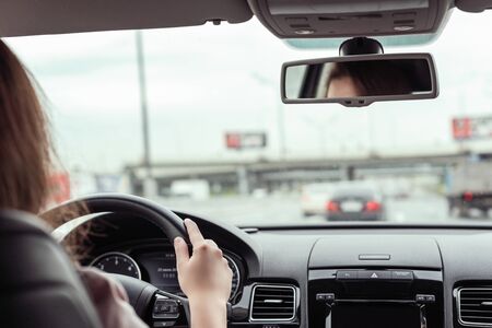 woman is driving on the highway under the bridge. View from the back seat of the carの写真素材
