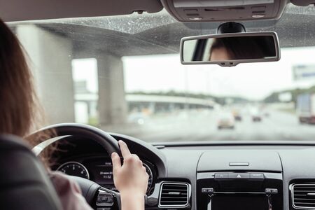 woman is driving on the highway. View from the back seat of the carの写真素材