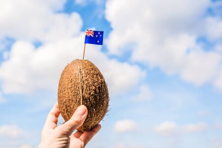 Tropical coconut with the Australian flag in the form of a toothpick in female hands. Travel concept.  tourist of Australia on vacationの写真素材