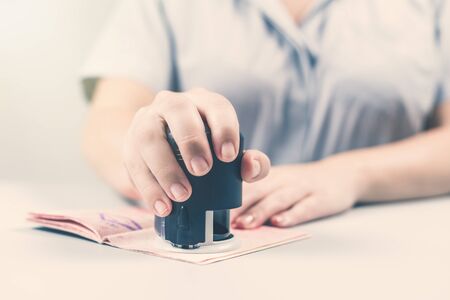 Immigration and passport control at the airport. woman border control officer puts a stamp in the passport. Conceptの写真素材