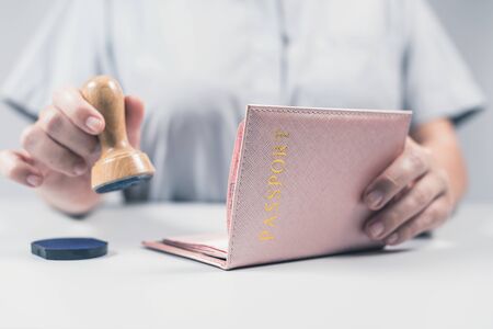 Immigration and passport control at the airport. woman border control officer puts a stamp in the Deutsch passport of German citizen. Conceptの写真素材