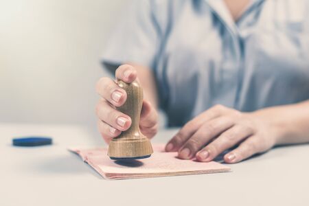 Immigration and passport control at the airport. woman border control officer puts a stamp in the passport. Conceptの写真素材