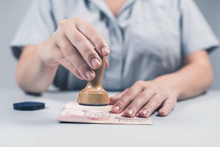 Immigration and passport control at the airport. woman border control officer puts a stamp in the passport. Conceptの写真素材