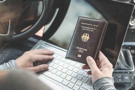 Woman in the car with laptop and germany passport. Travel concept.の写真素材