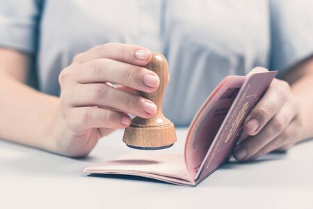 Immigration and passport control at the airport. woman border control officer puts a stamp in the passport. Conceptの写真素材