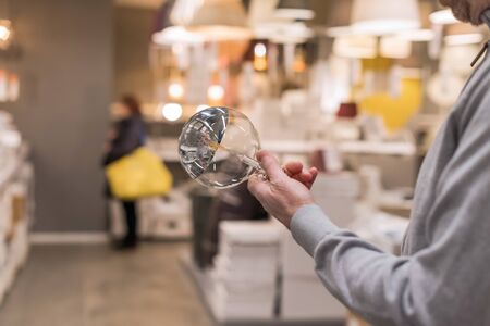 Man hand holding or selecting huge LED diode light bulb lamp in department store. Energy efficient lightingの写真素材