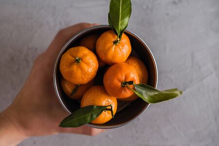 Mandarin in the small iron bucket on the grey concrete background. Still life. Flat layの写真素材