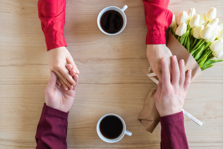 Valentines day.  Close-up of woman and man celebrating in restaurant. Boyfriend giving bouquet of...