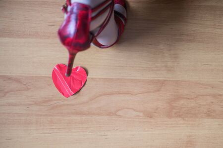 Legs of a woman in red high heel shoes stand on paper red crumpled heart on a floor. Heart broken concept. Copy Spaceの写真素材