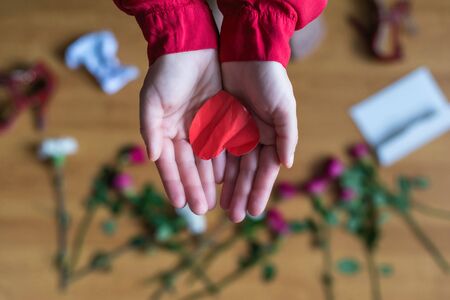 woman with crumpled paper heart in the hand sitting on the floor.  Broken relationships in bad Valentine's day. concept. Top viewの写真素材