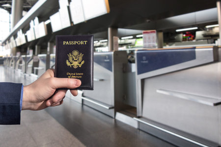 Man (businessman)  in a blue suit holding american passport in the airport opposite check-in area....