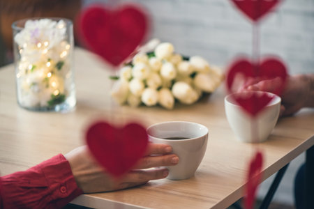 Valentines day.  Close-up of female and man celebrating in restaurant with gifts and flowers. View...