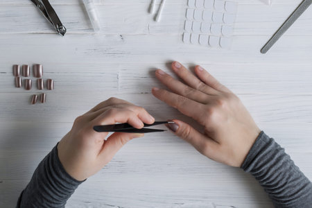 The process of putting artificial (fake) fingernail on the finger. Woman manicure. Flat lay.の写真素材