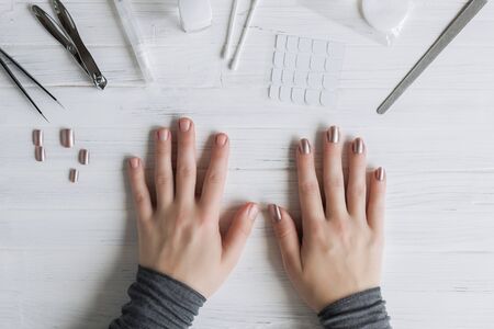 The process of putting artificial (fake) fingernail on the finger. Woman manicure. Flat lay.の写真素材