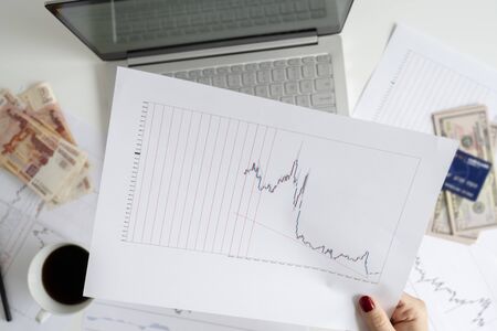 Woman freelancer. pack of banknotes fifty U.S. dollars, five thousand rubles, credit card and laptop with graphics and charts on office table. Forex exchange concept, Flat lay.の写真素材