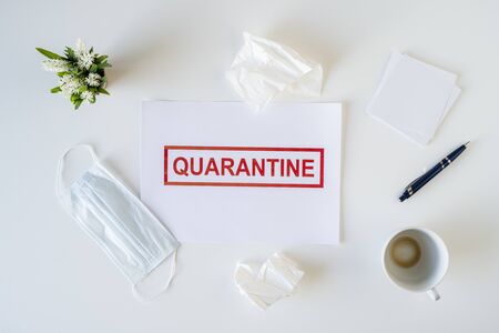 Abandoned workplace of a sick employee in the office due to coronavirus and quarantine with a used medical mask, napkins and a cup of finished coffee. Worldwide pandemic conceptの写真素材
