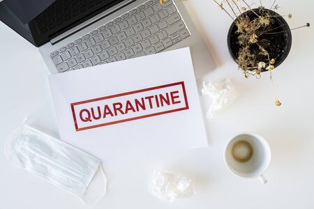 Abandoned workplace of a sick employee in the office due to coronavirus and quarantine with a used medical mask, napkins and a cup of finished coffee. Worldwide pandemic conceptの写真素材