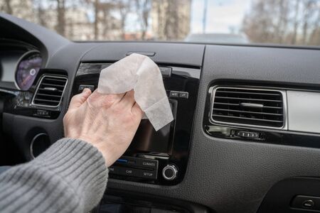 Man cleaning front dashboard of a car using antivirus antibacterial wet wipe (napkin) for protect himself from bacteria and virus.の写真素材