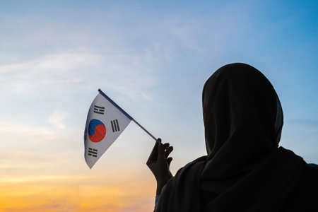 Silhouette of muslim woman in scarf with South Korea flag of at sunset. Concept