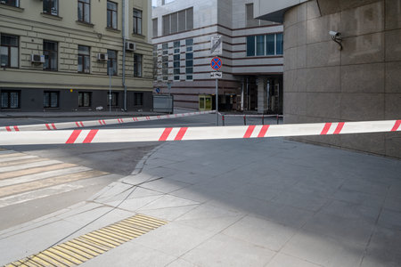 Empty urban street, roads and buildings with red and white restrictive tape. Quarantine. Self...