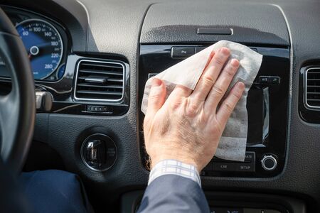 Middle age businessman in a blue suit cleaning front dashboard of a car using antivirus antibacterial wet wipe (napkin) for protect himself from bacteria and virusの写真素材