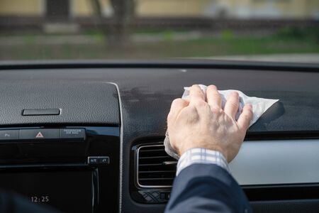 Middle age businessman in a blue suit cleaning front dashboard of a car using antivirus antibacterial wet wipe (napkin) for protect himself from bacteria and virusの写真素材