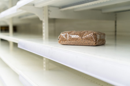 Shopping during virus outbreak. One packet of buckwheat on empty supermarket shelves. grocery store. pandemic. coronavirus. The concept of crisis and food shortagesの写真素材