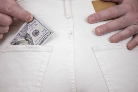 Pickpocket stealing. Man stel one hundred US dollar money from back woman pocketの写真素材