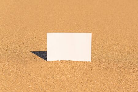 Mock up cardboard paper for text on sand beach. Close-up. Copy spaceの写真素材