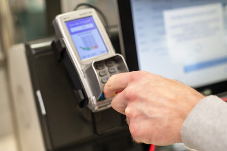 Man paying at the self-service counter entering credit card pin code for security password in credit...