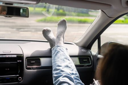 Woman passenger, legs in a jeans and socks on car dashboard while travel on the highway. Freedom  concept. の写真素材