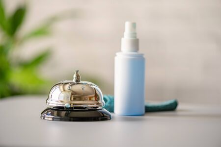 Cleaning ringing bell on reception desk. disinfection spray, small towel. Protection from bacteria and virus. Keeping health of guests. Hotel service. Selective focusの写真素材