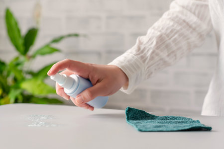 Hand of woman cleaning office desk. disinfection spray, small towel. Protection from bacteria and...