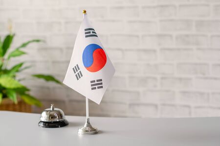 Silver vintage bell with national flag of South Korea on reception desk with copy space. Hotel service. Travel, tourism. Selective focus. Asia, Concept.の写真素材