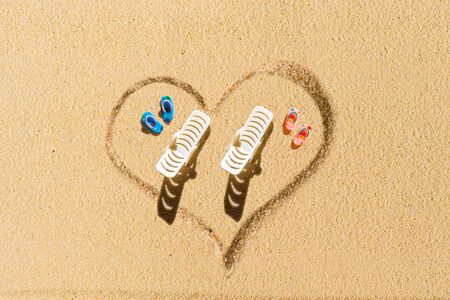 Aerial view of two pair of flip flops, sunbed in shape of heart on sandy tropical beach. Valentines day. Holiday concept. Creative, background, travel, summer. Flat layの写真素材