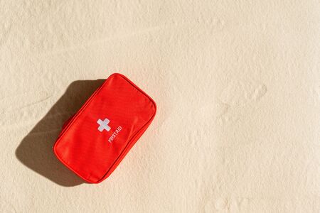 First aid kit red bag on the sand beach. Travel, flat lay, lifestyle.の写真素材