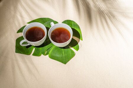 Cup coffee on sand of tropical beach under palm tree  branches shadow.の写真素材